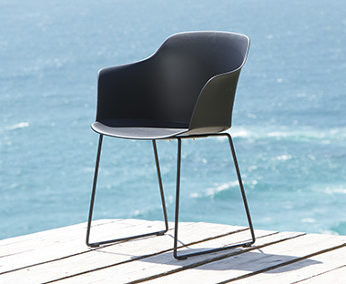 Udobna crna baštenska stolica od plastike sa metalnim nogama uz more
