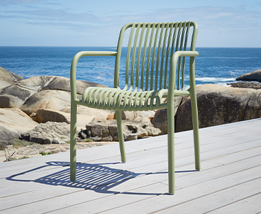 Baštenska stolica od plastike u zelenoj boji na terasi uz more