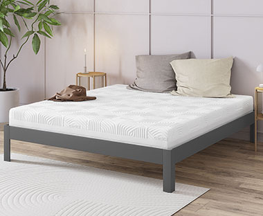 Veliki bijeli madrac za bračni krevet na okviru kreveta i ukrasni jastuci