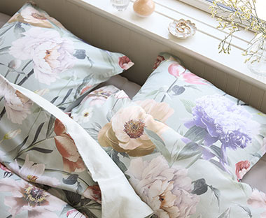 Krevet s jastucima i jorganom u lijepoj cvjetnoj posteljini