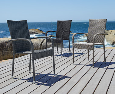 Tri pletene baštenske stolice na terasi pored mora