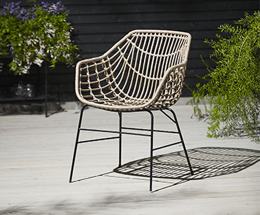 Pletena udobna baštenska stolica na osunčanoj terasi