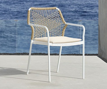 Lijepa bijela baštenska stolica sa pletenim naslonom za leđa na molu pored mora