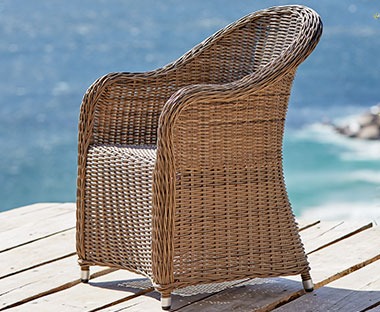 Masivna pletena baštenska fotelja na molu uz more