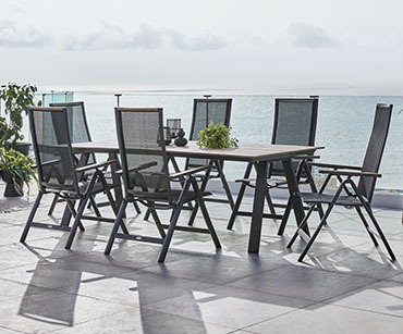 Dugački baštenski stol i crne baštenske stolice na terasi