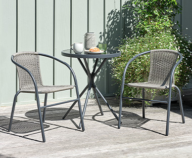 Bistro stolić od metala i dvije stolice od metala i imitacije ratana na terasi