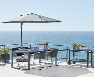 Baštenski stol i stolice na terasi ispod suncobrana