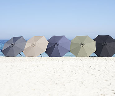 5 suncobrana u različitim bojama na pješćanoj plaži pod vedrim nebom
