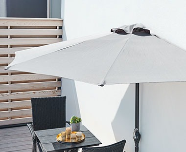 Balkonski suncobran iznad bistro stola sa dvije baštenske stolice