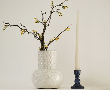 Lijepa bijela vaza sa reljefnim uzorkom i svijećnjak sa bjielom svijećom