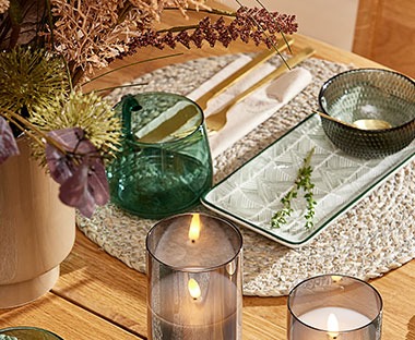 Lijepo uređen trpezarijski stol sa svijećama i elegantnim tanjirima