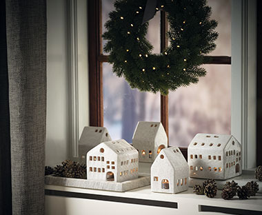 Lijepi fenjeriću i obliku bijelih kućica na prozoru ispod novogodišnjeg vijenca