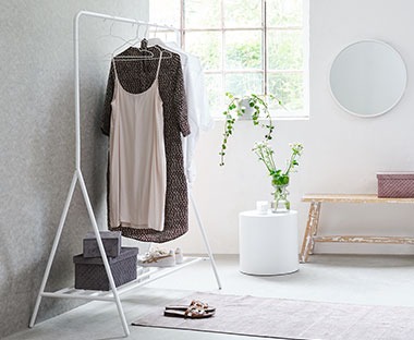 Elegantni bijeli metalni stalak za odjeću pred prozora kroz koji ulazi puno svjetla u hodnik