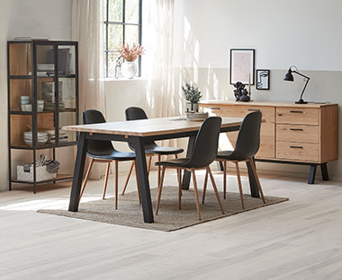 Trpezarija sa masivnim trpezarijskim stolom, stolicama skandinavskog dizajn, komodom i vitrinom