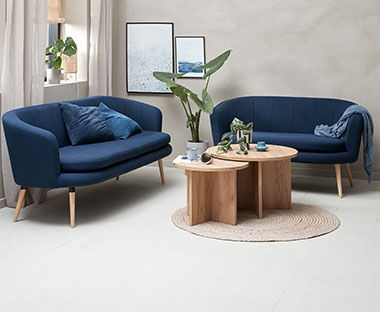 Dnevna soba sa dva plava kauča i dva mala drvena stolića