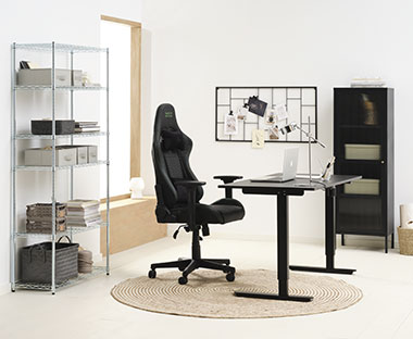 Radba soba s modernim radnim stolom podesive visine, crnom gejmerskom stolicom i malom crnom vitrinom