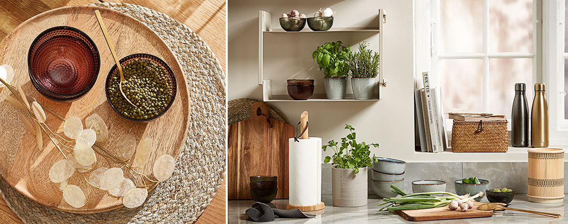 Staklene zdjele na pletenom podmetaču i kamene šoljice sa svježim začinskim biljkama na zidnoj polici u kuhinji