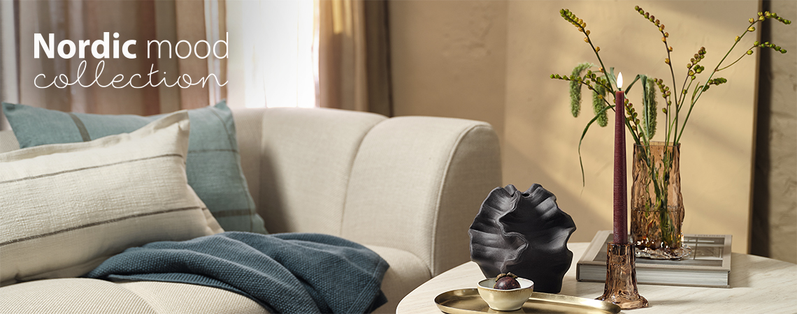 Dnevna soba sa kaučem i stolićem za kafu sa staklenom vazom i svijećnjakom