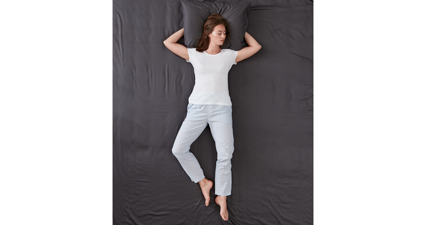 Žena spava na leđima sa rukama ispod jastuka