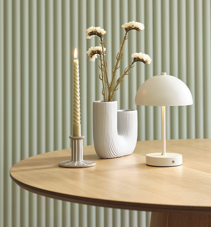 Elegantna lampa na baterije sa mesinganim detaljem, vaza i svijećnjak na drvenom stolu