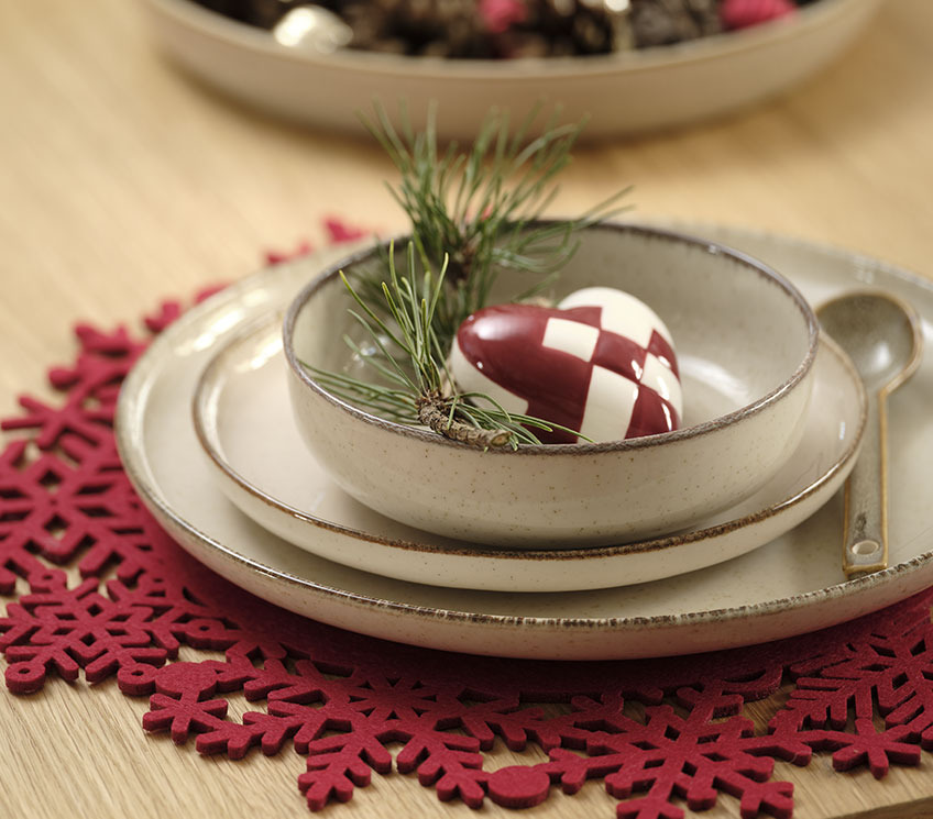 Crveni novogodišnji podmetač sa tanjirima, zdjelom i prazničnim dekoracijama
