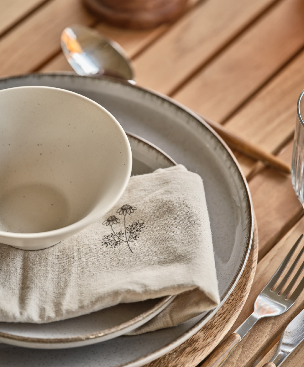 Sivi tanjiri, lijepa platnena salveta i bijela zdjelica na drvenom stolu
