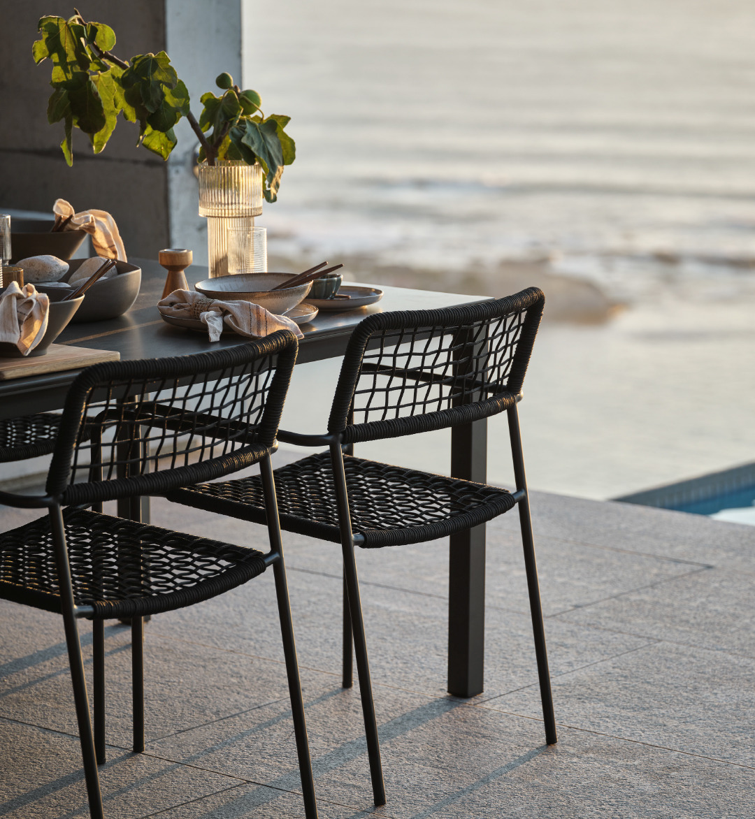 Čelične crne baštenske stolice uz crni baštenski stol na terasi