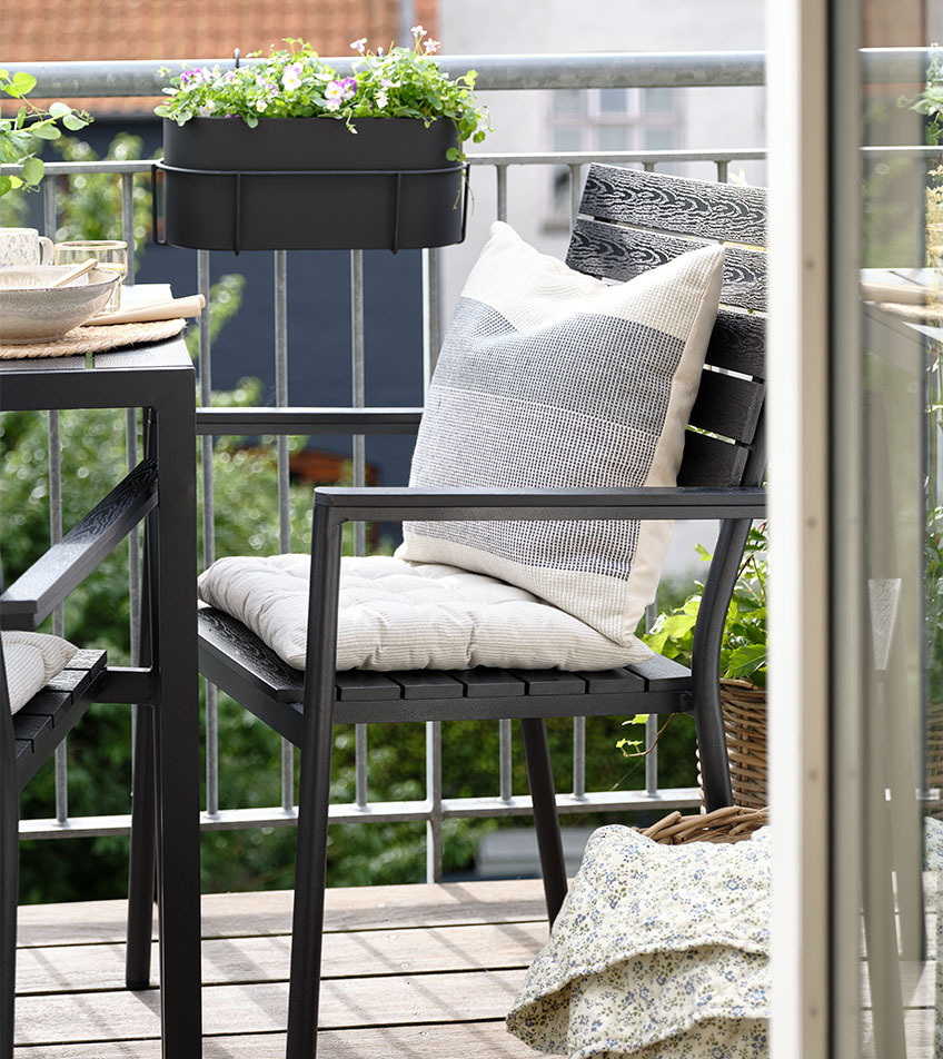 Crna složiva baštenska stolica sa jastucima na balkonu