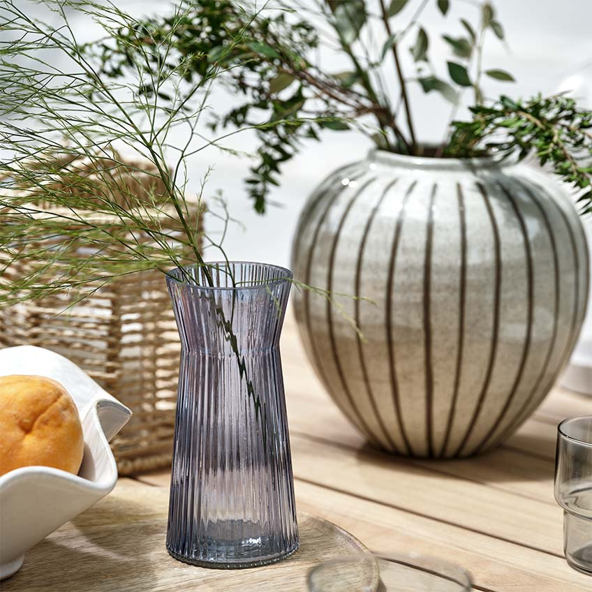 Vaza, fenjer i zdjela na drvenom baštenskom stolu