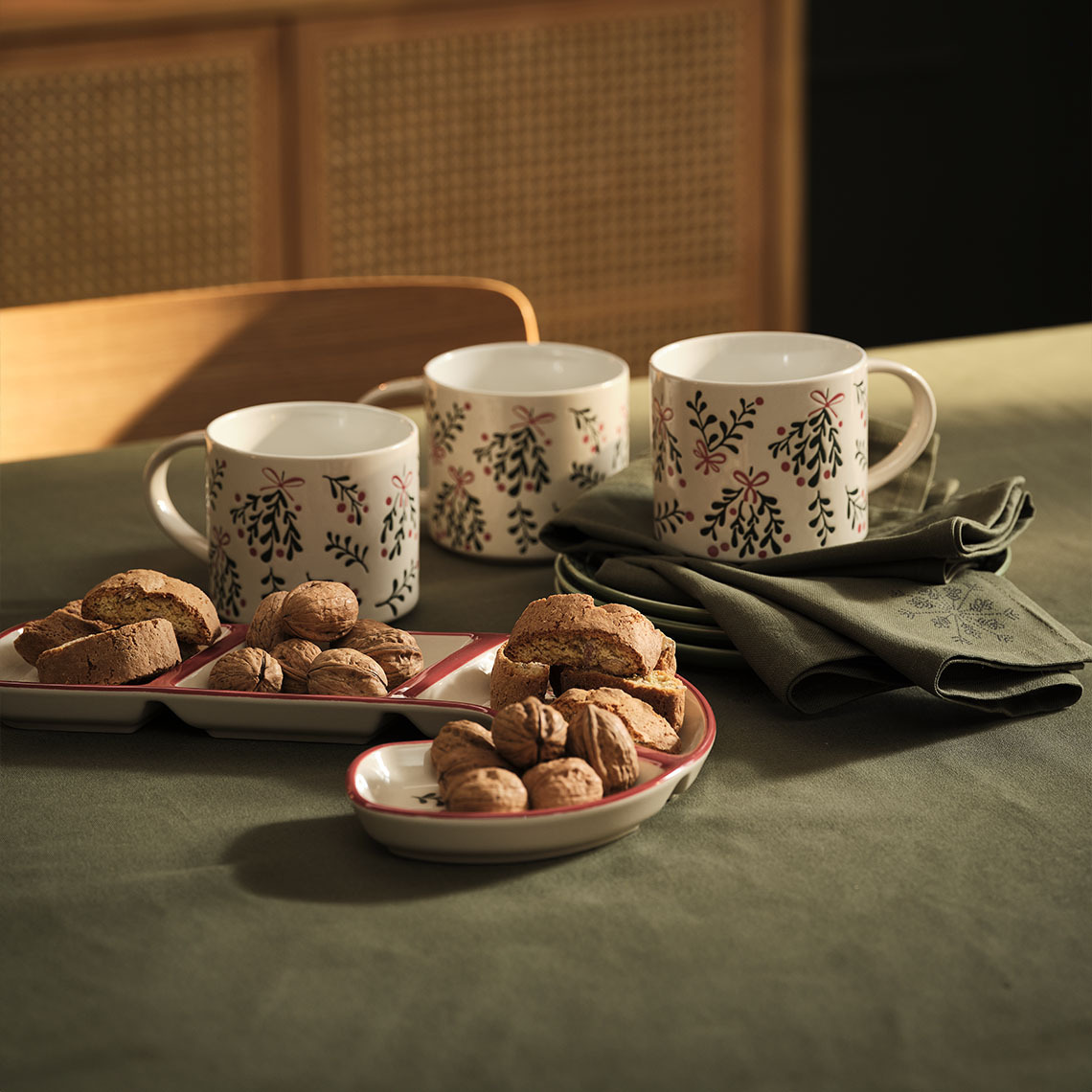 Božićne šalice, zdjela i božićne platnene salvete na stolu