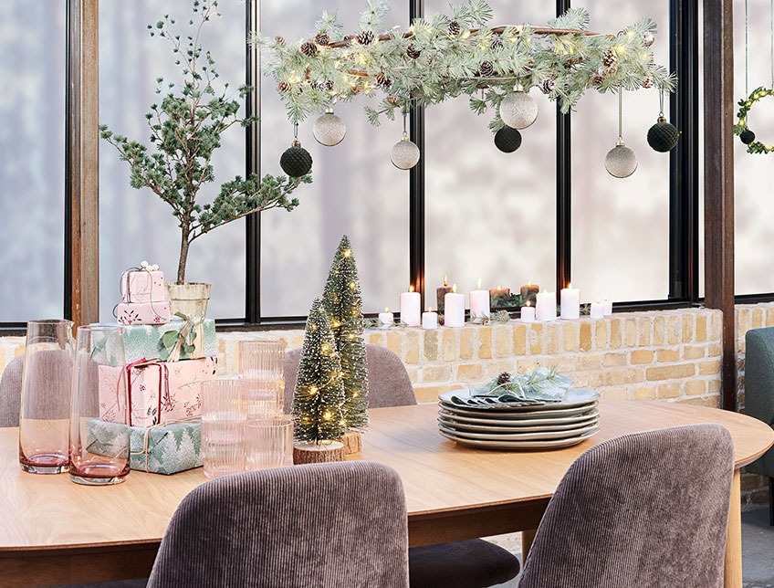 Praznični stol s novogodišnjim ukrasima, poklonima i tanjirima 
