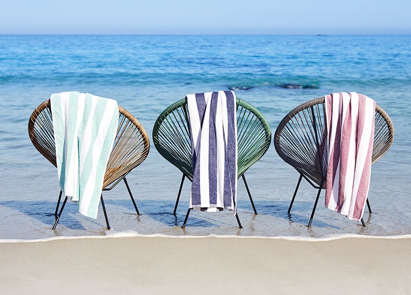 Lounge baštenske stolice na plaži sa velikim peškirima za plažu prebačenim preko naslona za leđa