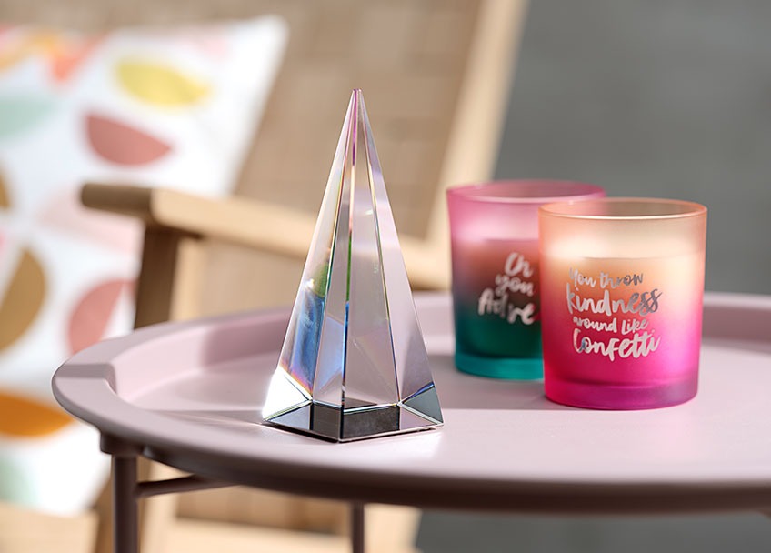 Kristalna piramida i dvije ukrasne svijeće na stoliću roze boje