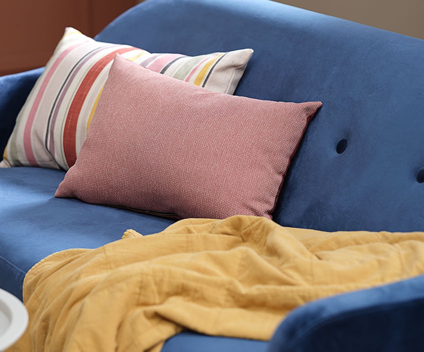 Šareni jastuci i štepana deka na plavom kauču