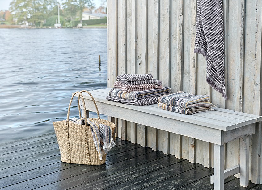 Luksuzni peškiri na klupi i pletena torba pored jezera