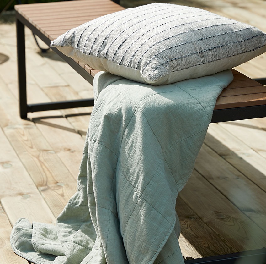 Drvena baštenska klupa sa dekom i jastukom