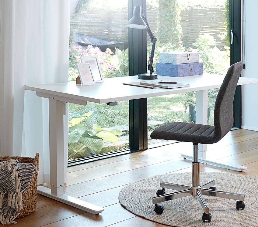 Kancelarijska stolica od tkanine i podesiv radni stol pored prozora