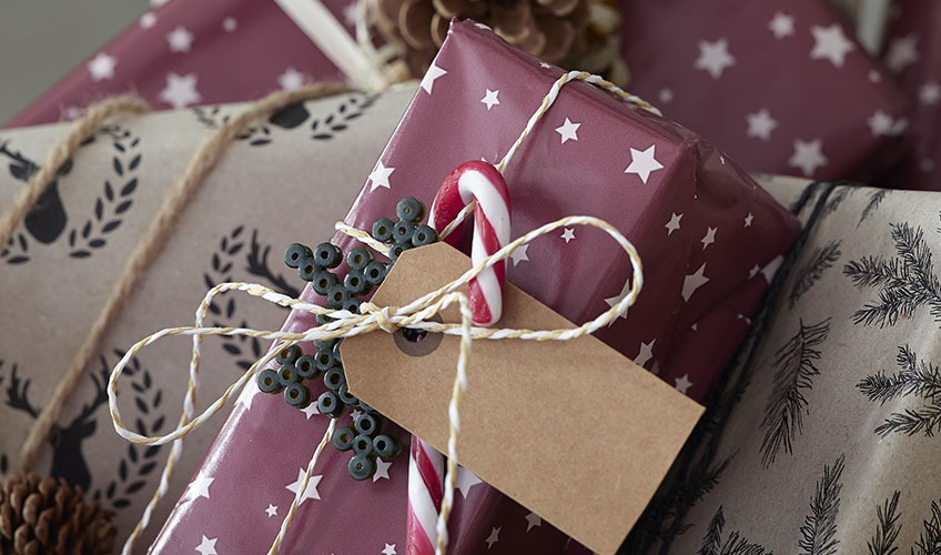 Novogodišnji poklon zamotan u papir i ukrašen bombonama i perlama
