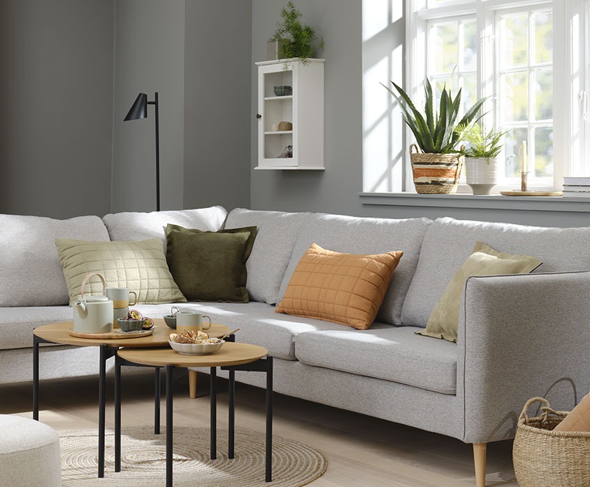AARHUS sofa, VALMUE jastuci i BRABRAND set stolića za kafu Dnevni boravak sa sivom sofom i narandžastim, zelenim i bež jastucima