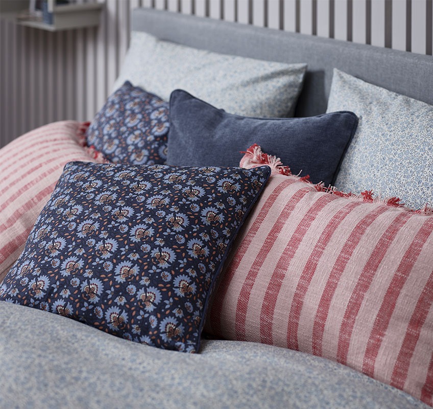Krevet sa ukrasnim jastucima u crvenim i plavim nijansama
