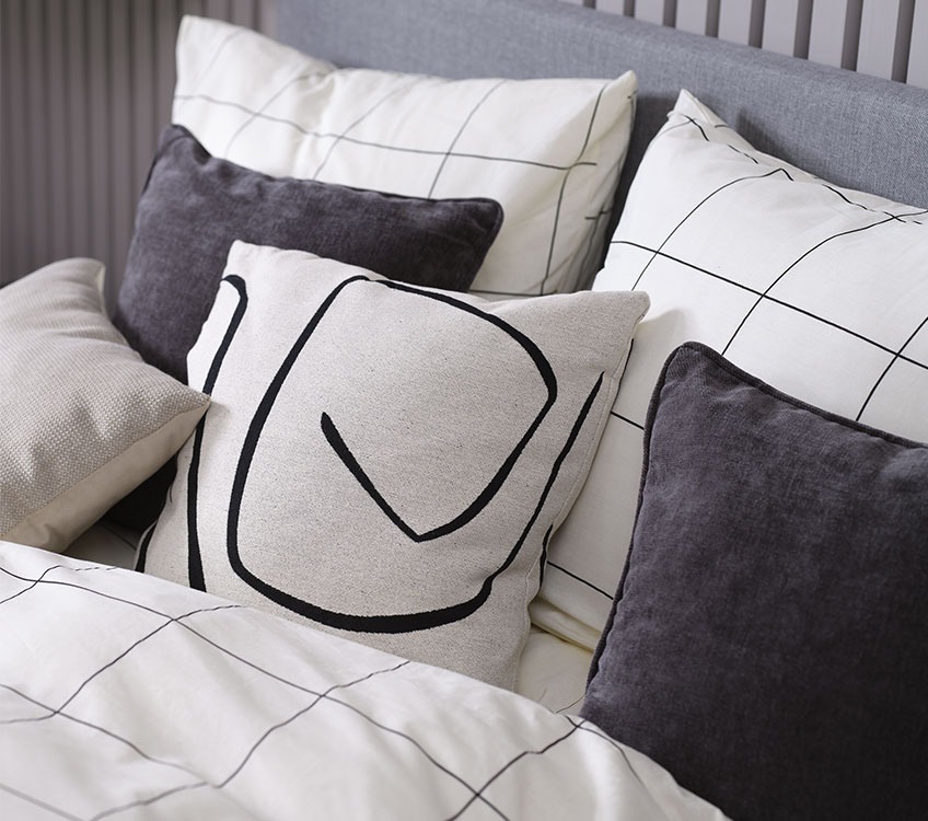 Spavaća soba sa crno-bijelom posteljinom i ukrasnim jastucima