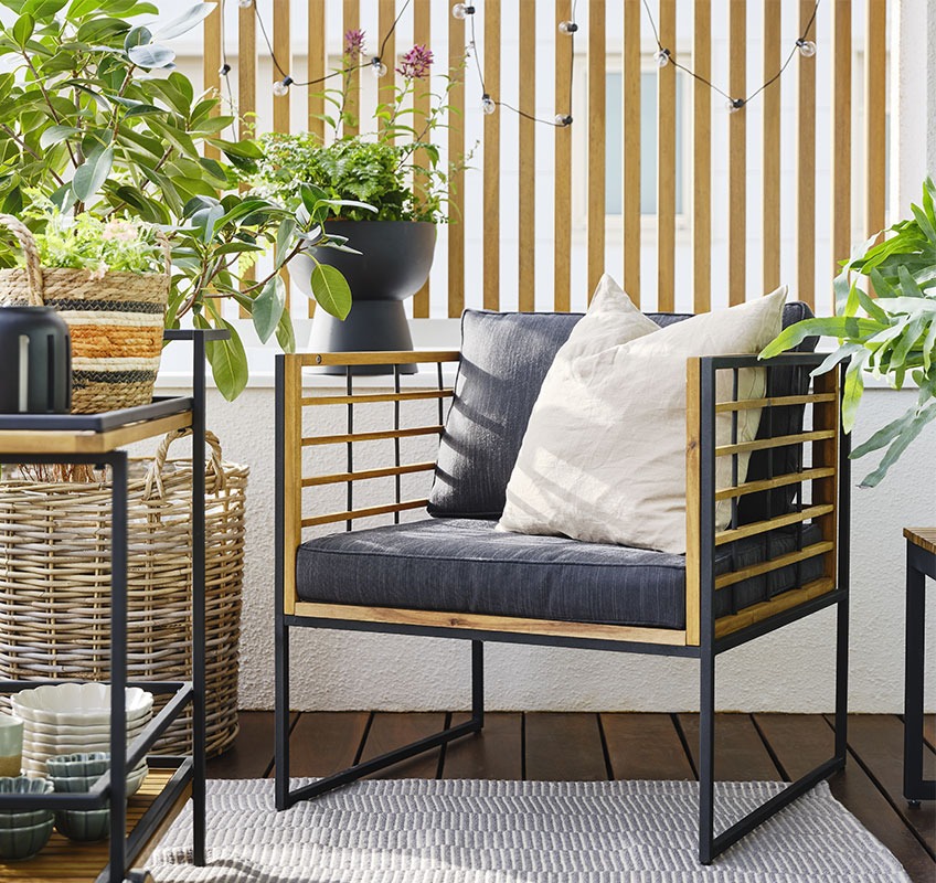 Balkon sa lounge stolicom od drveta i metala crne boje i biljke na njemu