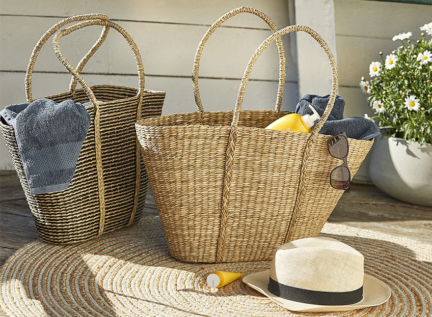 Dvije pletene torbe sa kremom za sunčanje i peškirima