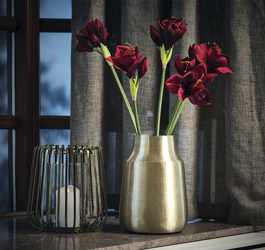 Fenjer i zlatna vaza sa umjetnim cvijećem na prozoru
