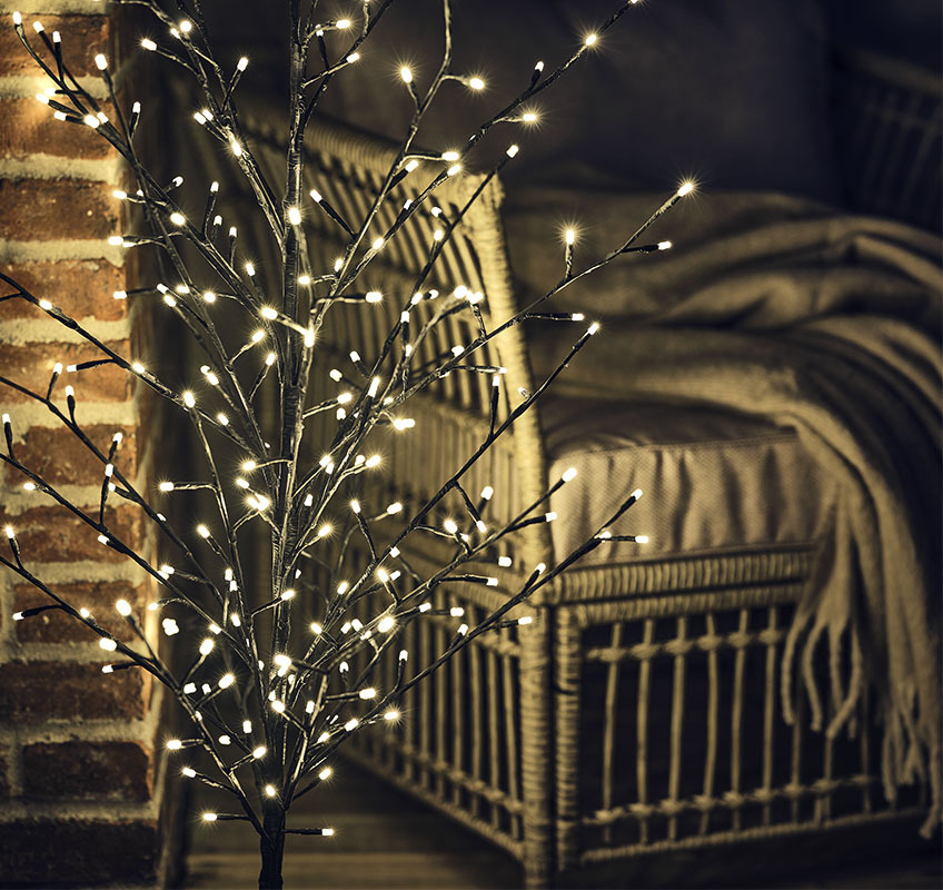 Close-up of small light tree in front of lounge chair