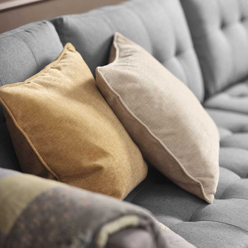 Žuti i bež ukrasni jastuci na sivoj sofi