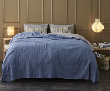 Krevet sa plavim prekrivačem za krevet, lampa i luster od pruća