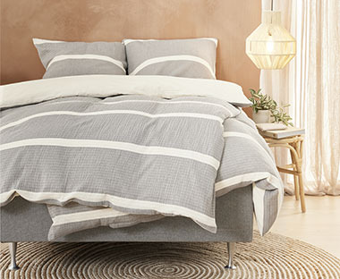 Krevet sa lijepom sivo bijelom posteljinom od pamučnog muslina