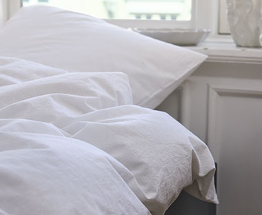 Lijepa bijela posteljina retro izgleda na krevetu pored prozora